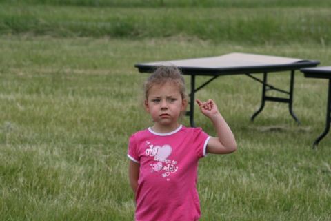 1990 Chevrolet Suburban - A young girl in a pink t-shirt stands in a grassy field with tables in the background.