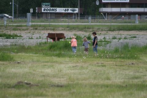 1990 Chevrolet Suburban - Children explore a field with a motel and highway in the background.