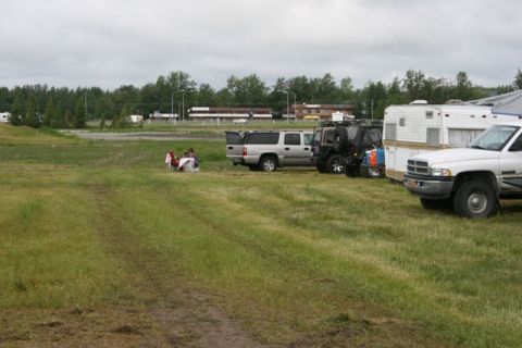 1990 Chevrolet Suburban - A group of vehicles and people are gathered in a grassy field on an overcast day.
