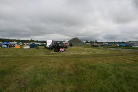 1990 Chevrolet Suburban - A large outdoor event is underway with numerous vehicles and tents set up across a wide grassy area.