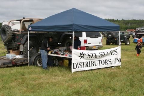 1990 Chevrolet Suburban - An outdoor event with vehicles, a tent, and a banner for Six States Distributors, Inc.