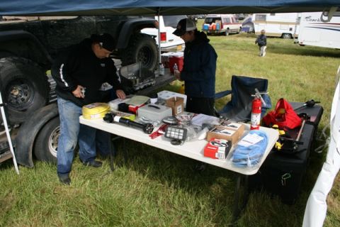 1990 Chevrolet Suburban - An outdoor event displays various automotive parts and accessories laid out on tables, with vehicles and campers visible in the distance.