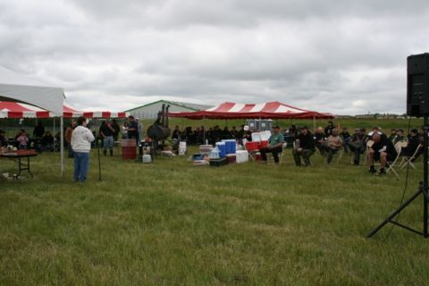1990 Chevrolet Suburban - An outdoor event with attendees seated and standing under tents on a cloudy day.