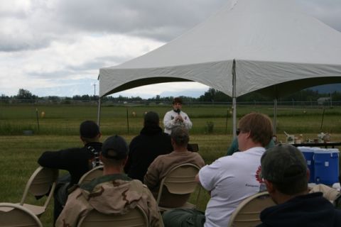 1990 Chevrolet Suburban - An outdoor event is taking place under a large tent, with a speaker addressing a seated audience.