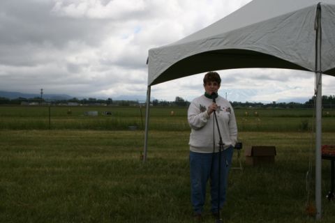 1990 Chevrolet Suburban - A woman speaks into a microphone while standing under a tent at an outdoor event.