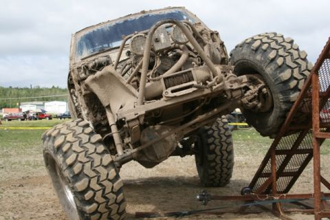 1990 Chevrolet Suburban - A heavily modified and mud-splattered off-road vehicle navigates a challenging obstacle course.