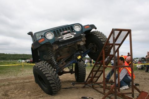 1990 Chevrolet Suburban - A modified Jeep Wrangler attempts to ascend a challenging obstacle during an off-road event.