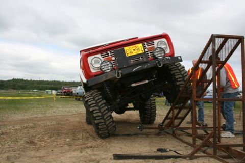 1990 Chevrolet Suburban - A red off-road vehicle is positioned on a metal ramp with two people nearby.