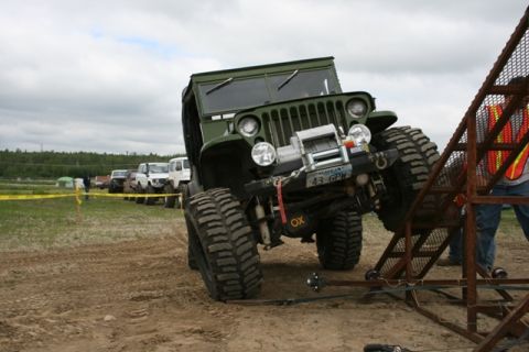 1990 Chevrolet Suburban - An off-road vehicle with oversized tires is positioned on a dirt track, with other vehicles in the background.