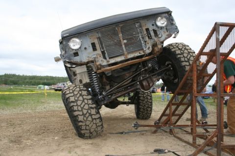 1990 Chevrolet Suburban - An off-road vehicle is positioned on a metal ramp, its modified suspension and large tires.