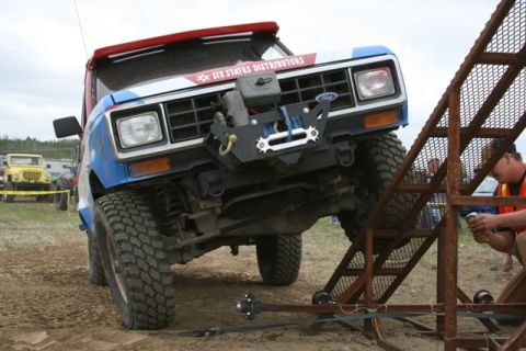 1990 Chevrolet Suburban - Off-road truck with winch and custom bumper navigates an obstacle course, with a yellow Jeep in the background.