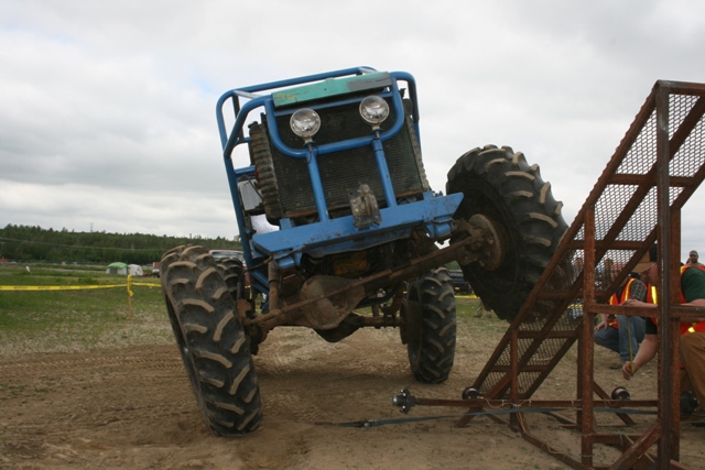 Blue off-road buggy with large tires on a ramp, rear view
