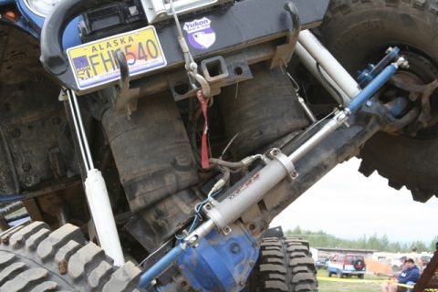 1990 Chevrolet Suburban - A close-up view of the rear suspension and undercarriage of a modified off-road vehicle, featuring large air springs, hydraulic shocks, and…