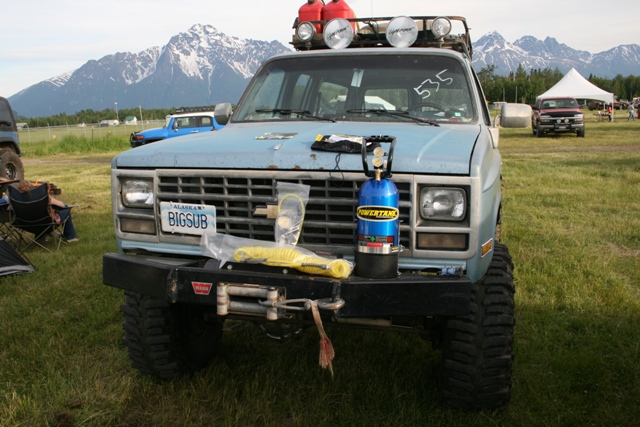 Front view of a light blue 1990s Chevrolet Suburban with a winch, Power Tank, and gas cans.