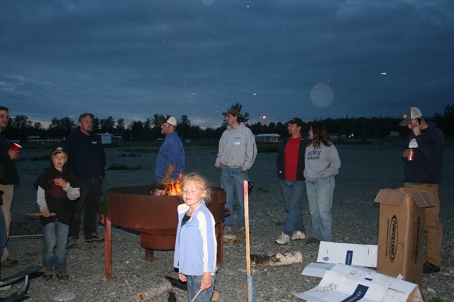 A group of people gathered around a fire pit at dusk.