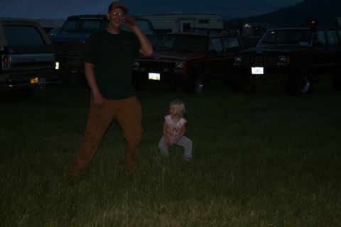 1990 Chevrolet Suburban - A man in a green shirt and brown pants poses in a grassy field at dusk, with several SUVs parked behind him. A young child in a pink shirt…