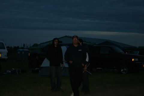 1990 Chevrolet Suburban - A dark Chevrolet pickup truck is parked in a grassy field at dusk, with two people standing in front of it and a tent set up nearby.