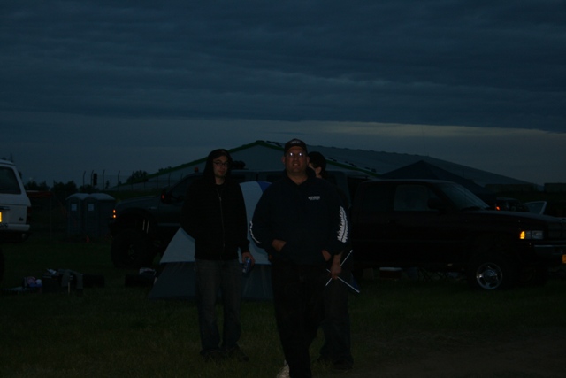 Dark Chevrolet pickup truck parked at dusk with two people and a tent.