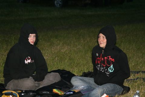 1990 Chevrolet Suburban - Two young people wearing hooded sweatshirts sit on the grass at night.