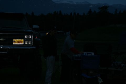1990 Chevrolet Suburban - A black Chevrolet pickup truck is parked in a dimly lit outdoor setting with two men standing near the tailgate. The truck's license plate…