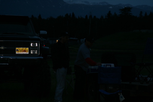 Black Chevrolet pickup truck with license plate FHT493 ALASKA, parked outdoors at dusk.