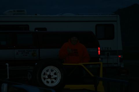1990 Chevrolet Suburban - A person wearing an orange hoodie gives a thumbs up while standing next to a trailer and a dark colored van or SUV. A large RV is parked be…