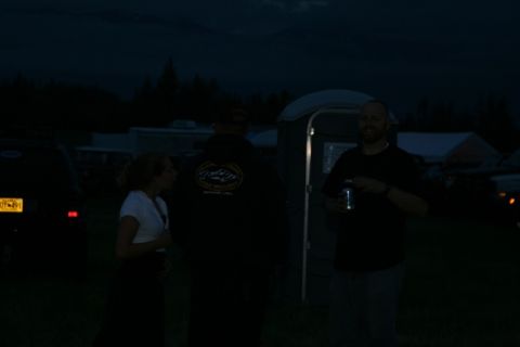 1990 Chevrolet Suburban - Three people are standing outdoors at dusk. A portable toilet is visible behind two of the individuals.
