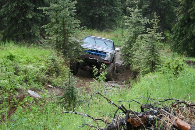 Lifted Chevrolet pickup truck on a muddy forest trail.