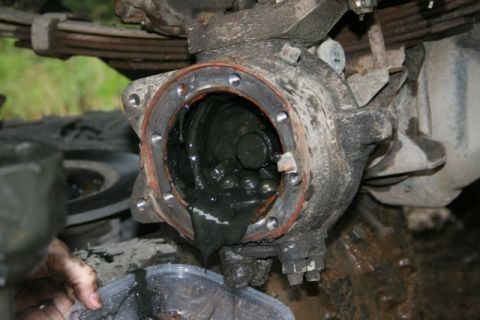 1990 Chevrolet Suburban - The open differential housing of a heavily soiled vehicle is shown, with thick, dark grease dripping into a clear plastic container below.…