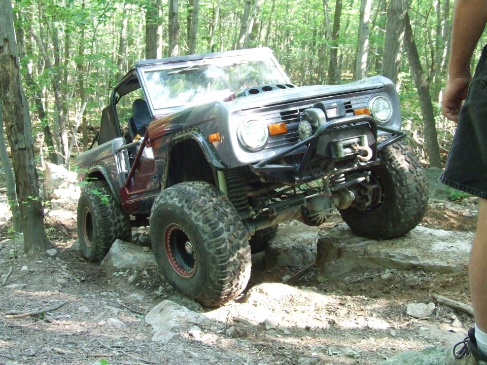 Modified classic Ford Bronco on a rocky off-road trail.