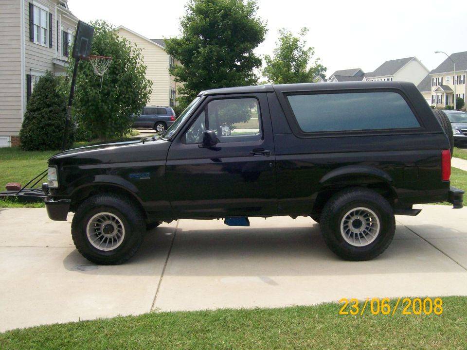 Black full-size two-door SUV with shell top, lifted on alloy wheels in a driveway