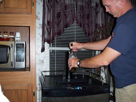 1996 Ford Bronco - A man is pouring beer from a kegerator into a glass. The kegerator is black and has a digital display showing "38".