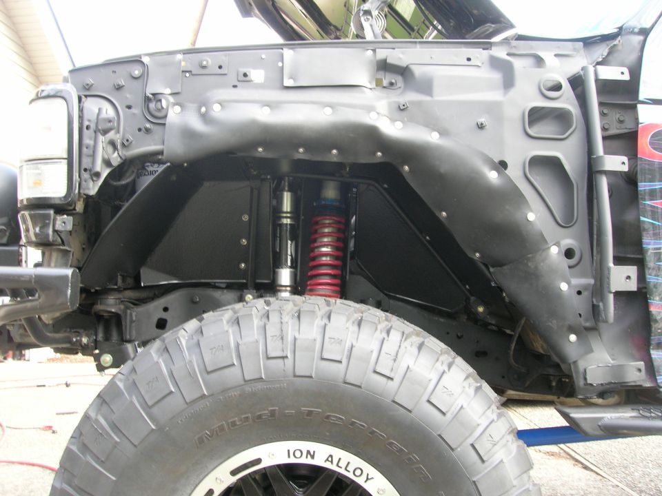 Front wheel well with red coilover and bypass shock over a Mud-Terrain tire