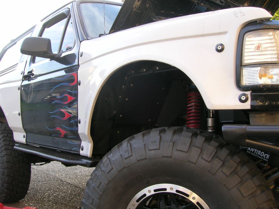Lifted SUV front corner with red coil-over shock, Antirock bar and mud tire