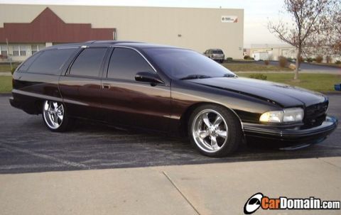 1998 Ford Crown Victoria - Side view of a black Chevrolet Caprice station wagon on chrome wheels in a parking lot.