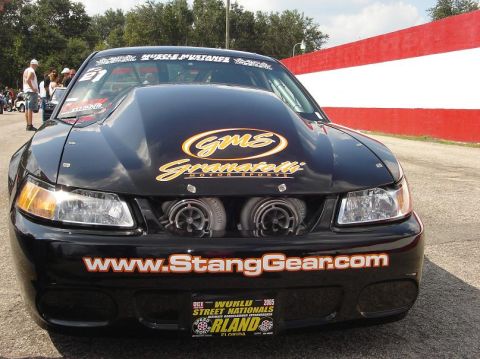 1998 Ford Crown Victoria - Front view of a black drag-racing Ford Mustang with sponsor graphics and twin air intakes.