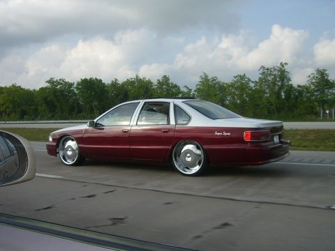 1998 Ford Crown Victoria - Rear three-quarter action shot of a maroon Chevrolet Impala SS sedan on the highway.