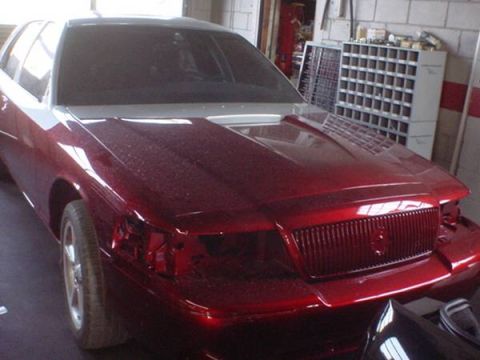 1998 Ford Crown Victoria - Front view of a metallic candy red Mercury sedan undergoing paint and bodywork in a garage.