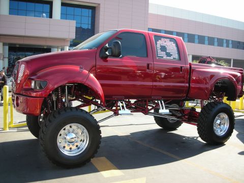1998 Ford Crown Victoria - Heavily lifted candy red Ford F-650 crew cab truck displayed in a parking lot.