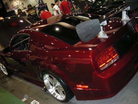 1998 Ford Crown Victoria - Rear three-quarter view of a candy red custom Ford Mustang displayed at an indoor event.