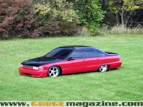 1998 Ford Crown Victoria - Side view of a lowered two-tone red and black Chevrolet Caprice sedan parked on grass.