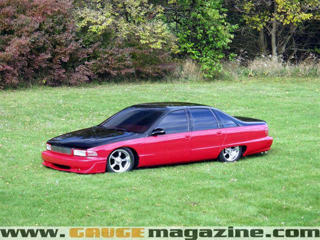Red and black lowered Chevrolet Caprice on grass