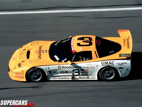 1998 Ford Crown Victoria - Side action shot of an orange and silver number 3 Goodwrench Corvette race car on a track.