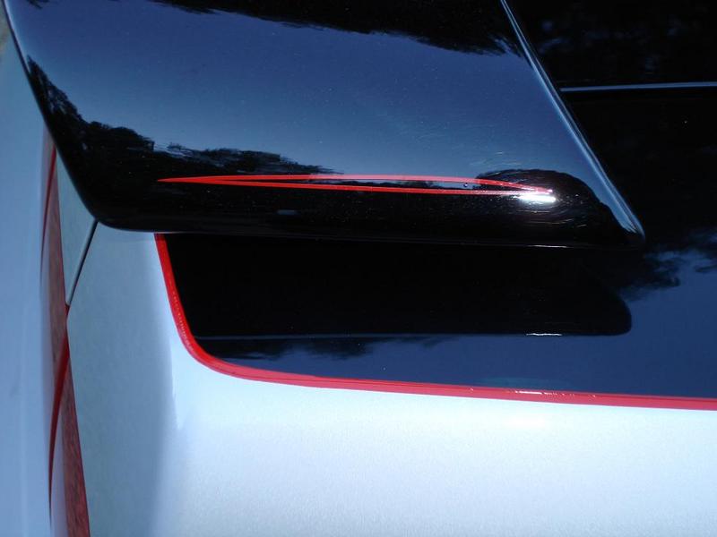 Close-up of a black rear spoiler with red pinstriping on a silver car