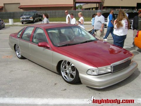 1998 Ford Crown Victoria - Photograph of a lowered two-tone red and gold Chevrolet Caprice sedan at an outdoor car show.