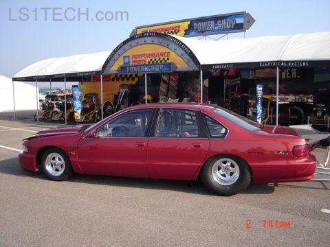 1998 Ford Crown Victoria - Photograph of a red Chevrolet Impala SS drag car parked near a GM Performance Parts vendor display.