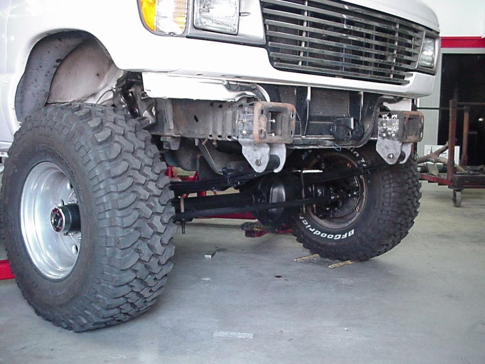White Ford truck front undercarriage with lifted axle and large BFGoodrich mud tires