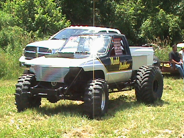 Modified pickup truck with large tires and custom grille, text "Mudd Dobber" on door.