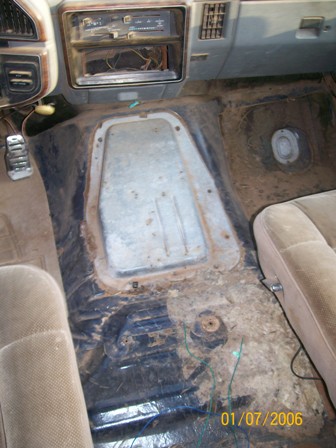 1988 Ford Bronco - The interior floor of a 1988 Ford Bronco shows exposed metal and dirty carpeting, indicating a need for restoration.