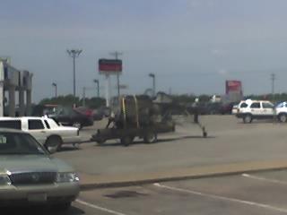 1992 Ford Bronco - A parking lot scene with multiple vehicles and a trailer is visible under a cloudy sky.